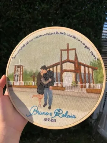 Bordado de um casal em frente a uma igreja de madeira