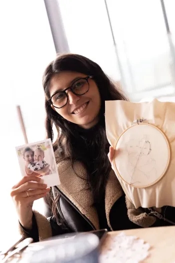Gabriela Alves segurando a foto original e o bastidor com o risco