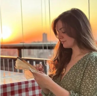 Jaque Rodrigues segurando um bordado ao pôr do sol