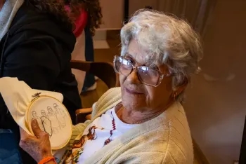 Zezé Vasconcelos segurando o bastidor com o risco da família